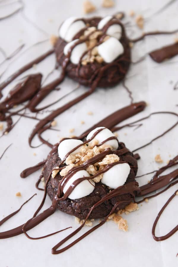 Chocolate s'mores cookie on parchment drizzled with chocolate.