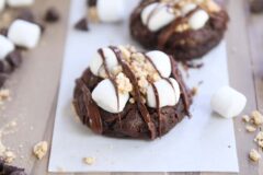 two chocolate s'mores cookies on white parchment paper