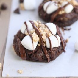 two chocolate s'mores cookies on white parchment paper