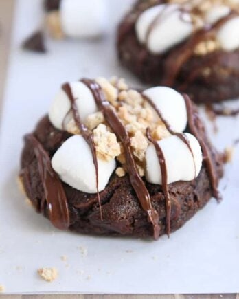 two chocolate s'mores cookies on white parchment paper