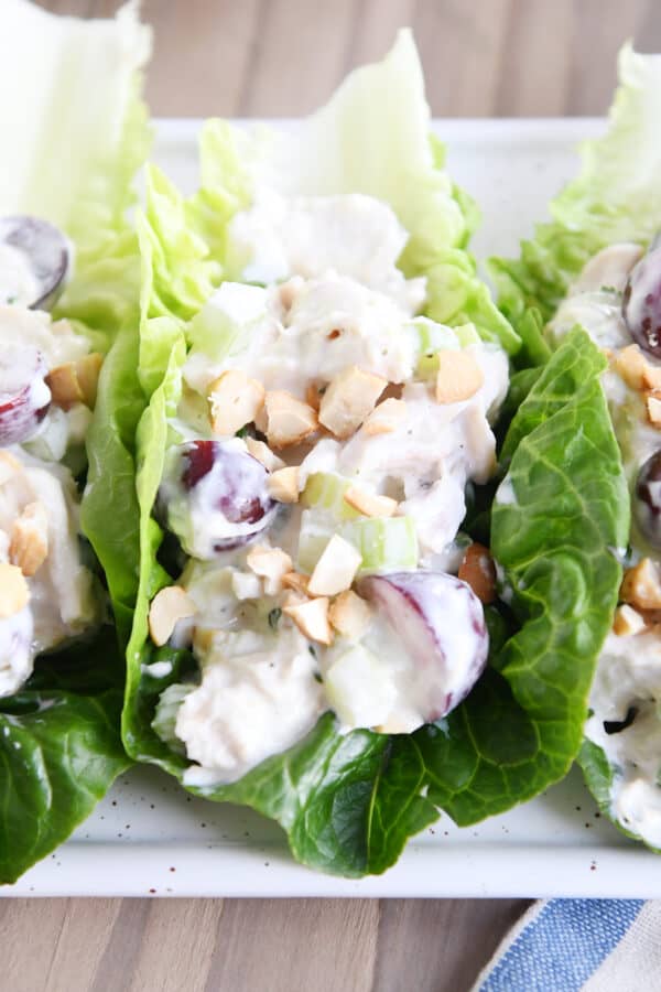 Chicken salad recipe on bed of lettuce leaves on white platter.