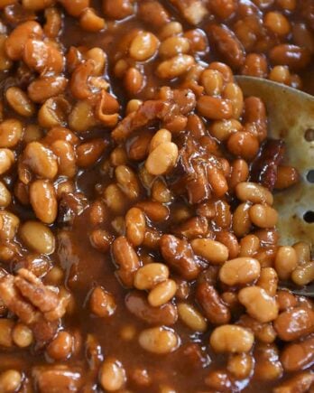 slotted spoon in dish of saucy baked beans