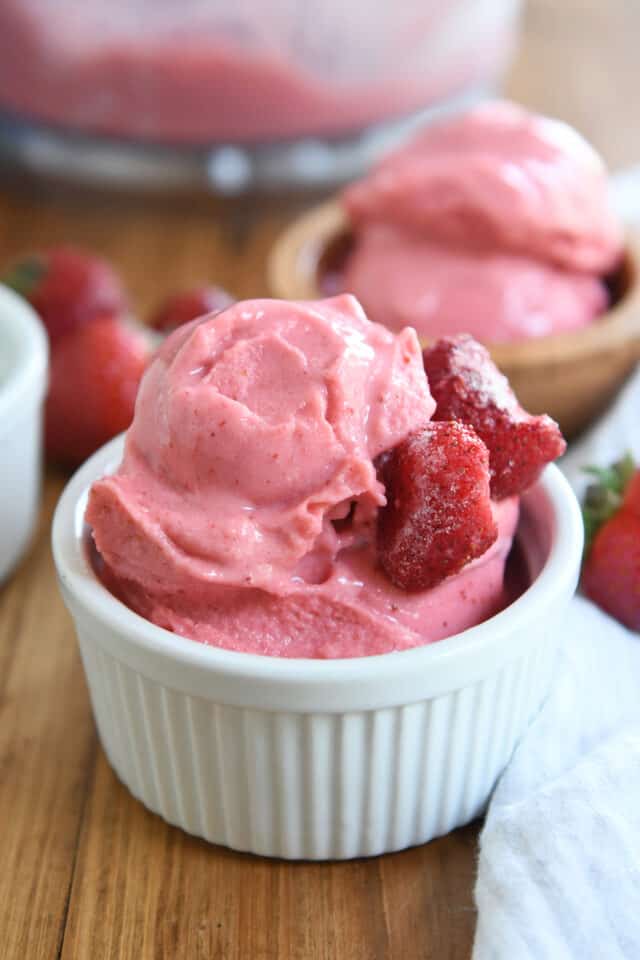 Homemade frozen strawberry yogurt in a white cup with a silver spoon