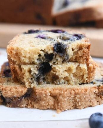 loaf of blueberry muffin bread split in half on top of full slice of bread