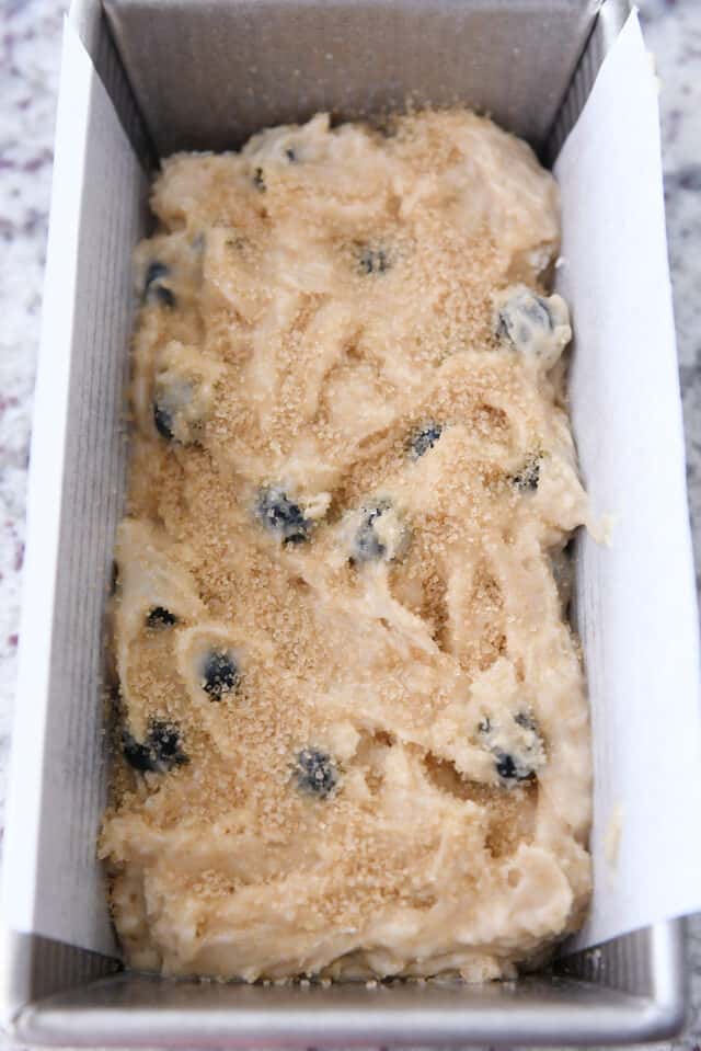 Blueberry muffin bread batter in loaf pan topped with coarse sugar.