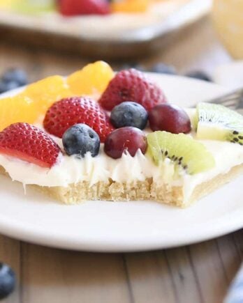 square of the best fruit pizza with bite taken out on white plate