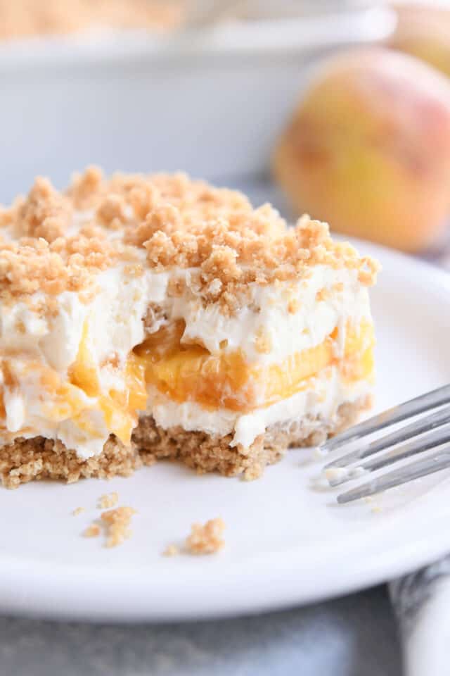 Square of peaches and cream dessert on white plate with fork.