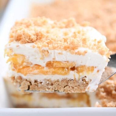 Square of peaches and cream dessert on a metal spoon