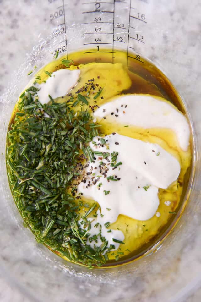 Fresh rosemary, ranch dressing, olive oil, salt in liquid measuring cup.