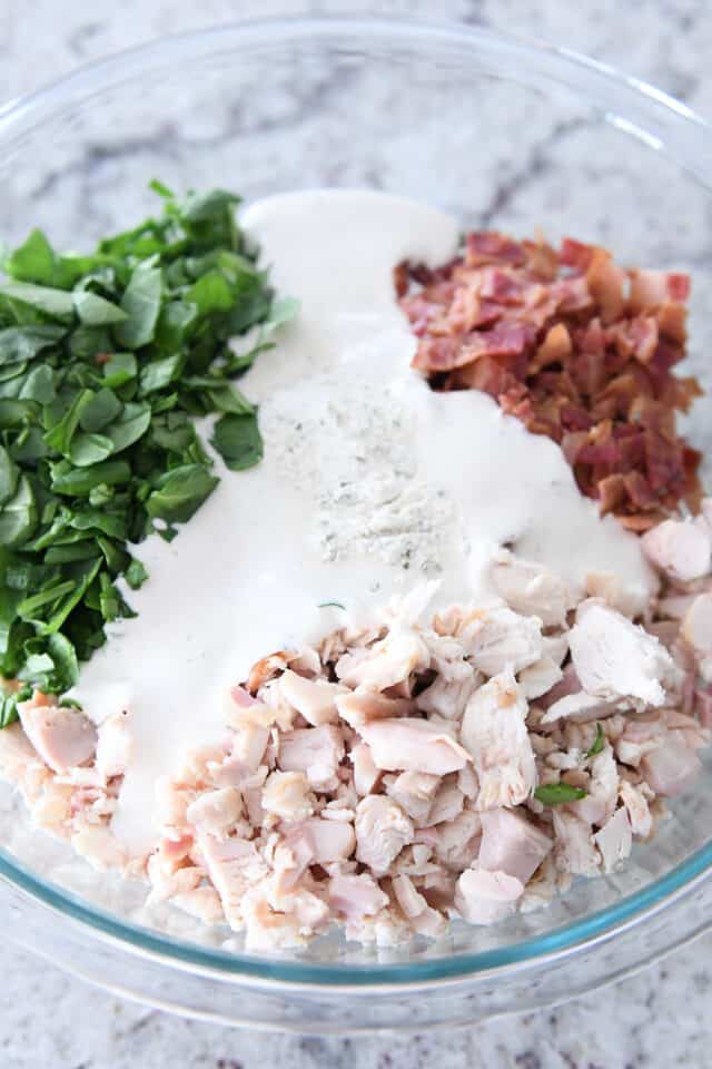 Glass bowl with chicken, spinach, bacon, ranch dressing.