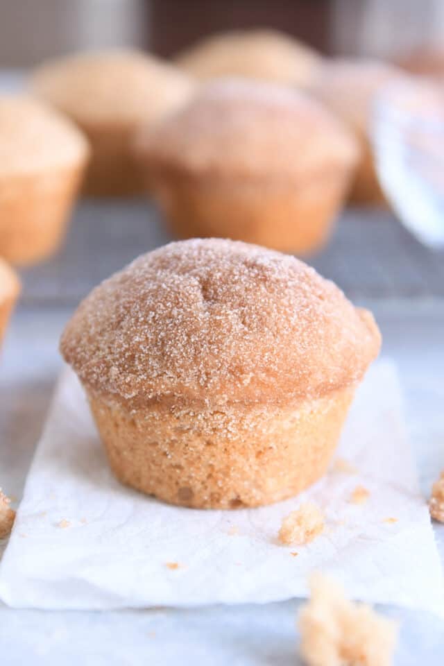 Cinnamon sugar doughnut muffin on white napkin with crumbs around napkin.