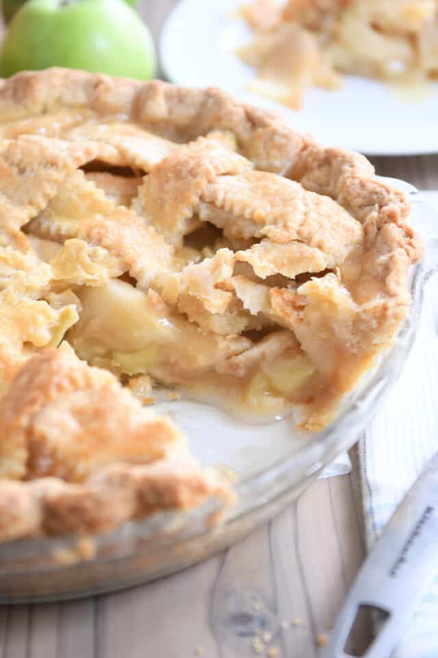 slice taken out of apple pie in glass pie pan