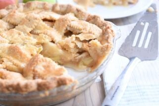 piece taken out of apple pie in glass pie pan