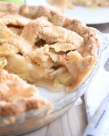 piece taken out of apple pie in glass pie pan