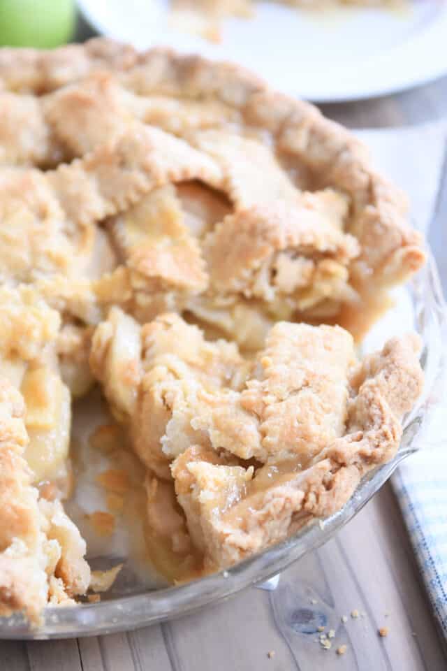 Piece of the best apple pie in glass pie pan.