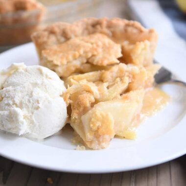 slice of apple pie on white plate with vanilla ice cream