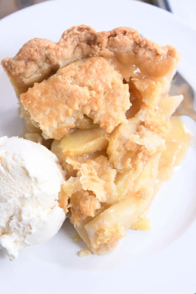 Top down view of best apple pie on white plate with vanilla ice cream.