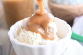 drizzling butterscotch sauce over vanilla ice cream in white bowl