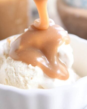 drizzling butterscotch sauce over vanilla ice cream in white bowl
