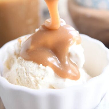 drizzling butterscotch sauce over vanilla ice cream in white bowl