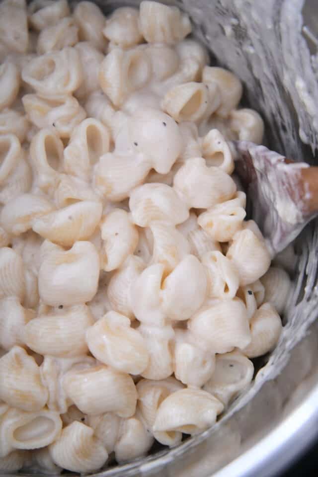 Pasta shells with creamy alfredo sauce in insert of electric pressure cooker.