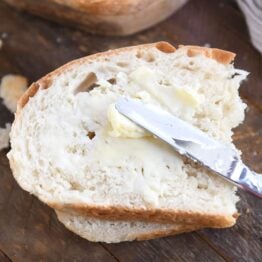 spreading butter on half slice of peasant bread with butter knife