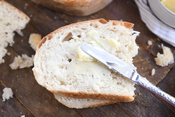 spreading butter on half slice of peasant bread with butter knife