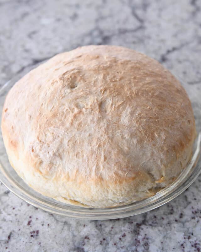baked loaf of peasant bread in glass pie plate