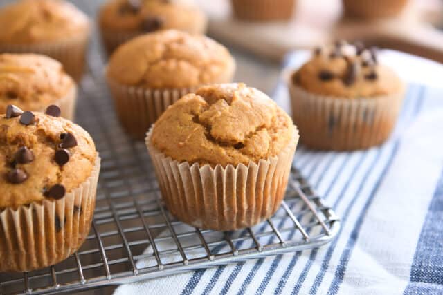 Sourdough pumpkin muffin in brown paper liner on metal cooling rack.