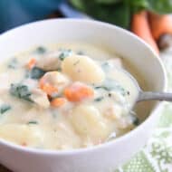 spoon scooping out bite of creamy chicken gnocchi soup in white bowl