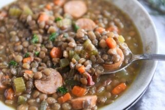 spoon lifting up small scoop of lentil soup in stone bowl