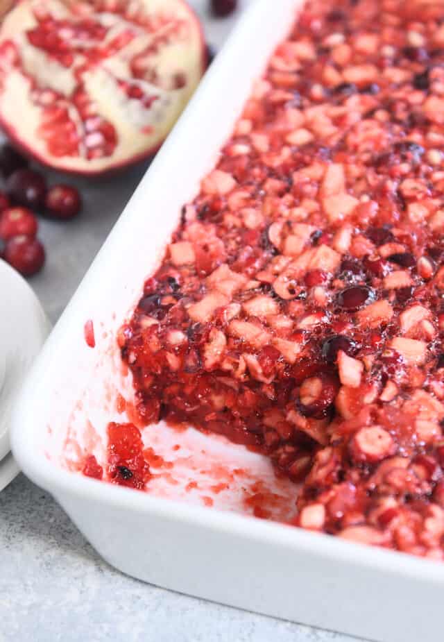 Square cut out in 9X13-inch white dish filled with cranberry pomegranate jello salad.