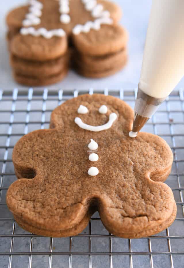 Piping decorations on gingerbread cookie with white icing.