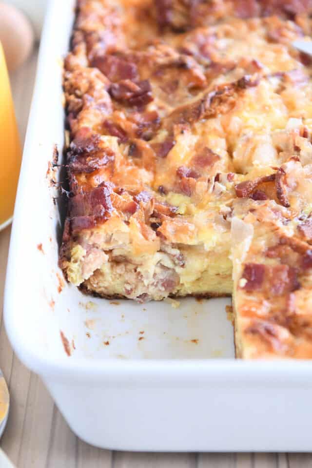 Overnight croissant breakfast casserole baked in white 9X13-inch pan with one serving removed.