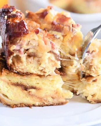 cheese strings pulling as fork takes bite from breakfast casserole on white plate