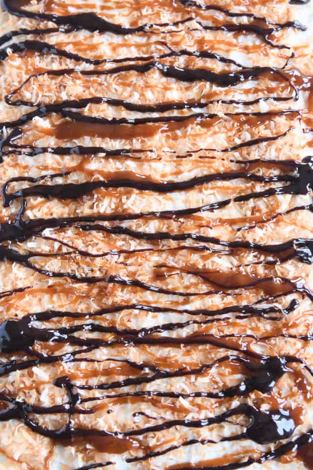 Top down view of toasted coconut and drizzled caramel and hot fudge sauce on top of whipped cream.