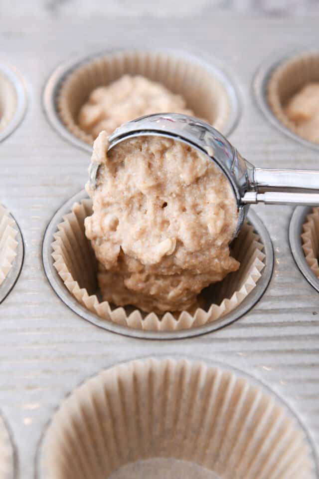 Scooping muffin batter into tin with cookie scoop.