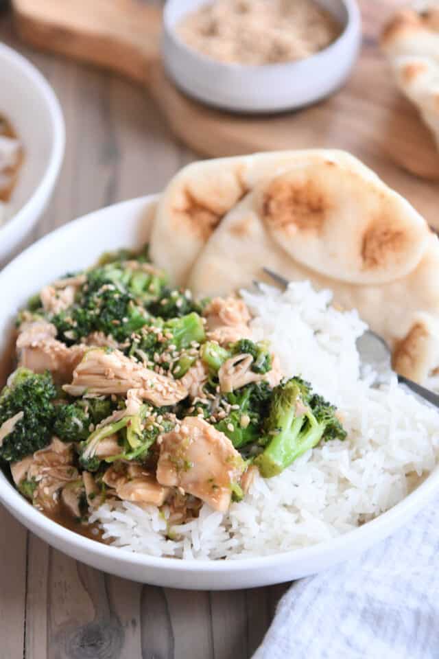 Naan bread in white bowl with rice, chicken, broccoli and brown sauce.