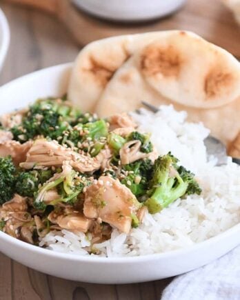 naan bread in white bowl with rice, chicken, broccoli and brown sauce