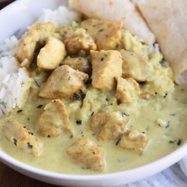 basil chicken in coconut curry sauce over rice with naan in white bowl