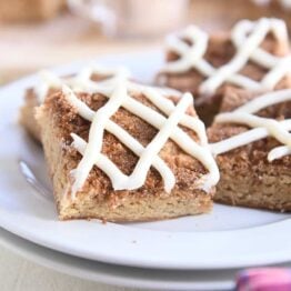 four cinnamon roll bars on two stacked white plates