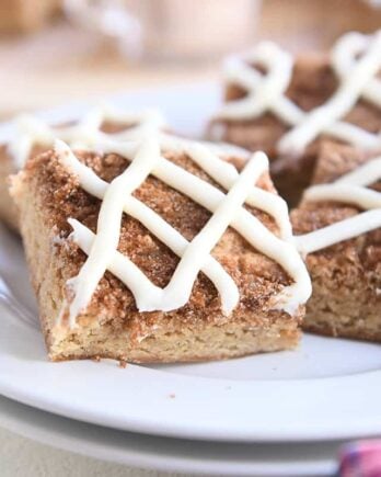 four cinnamon roll bars on two stacked white plates