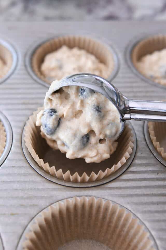 scooping muffin batter into tin with cookie scoop