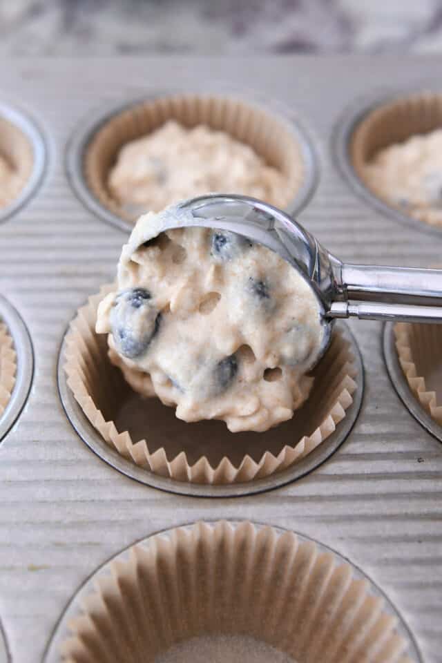 Scooping muffin batter into tin with cookie scoop.