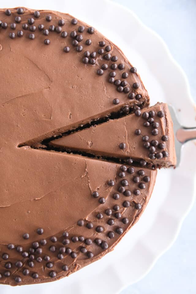 Top down view of frosted chocolate cake with piece sliced.