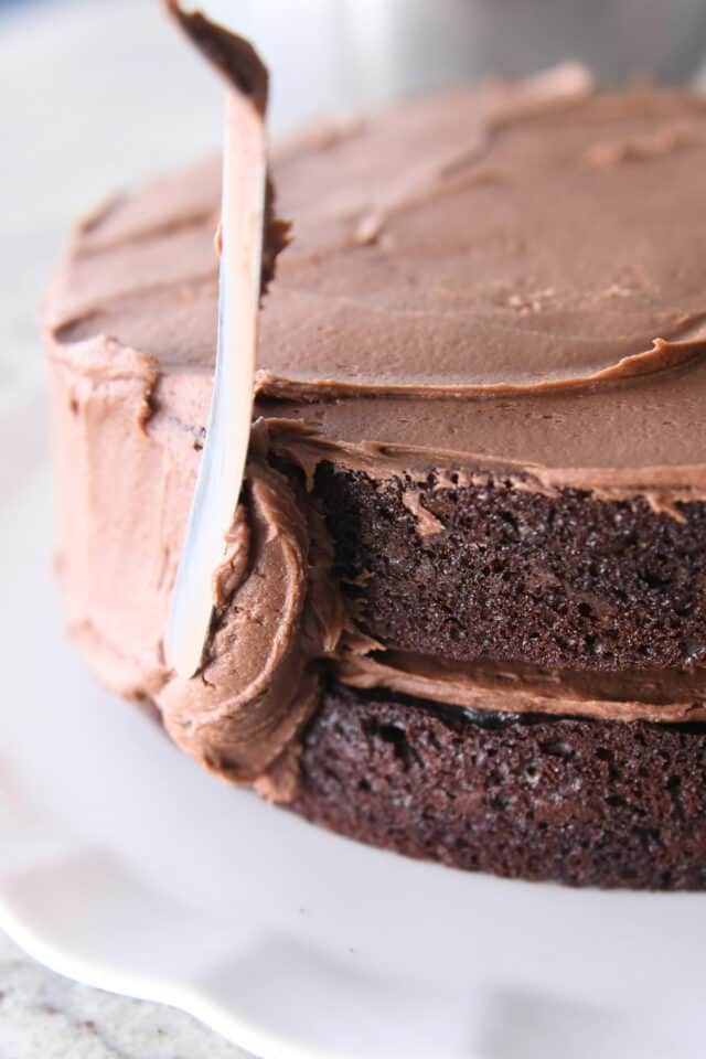 Frosting chocolate cake with chocolate frosting and offset spatula.