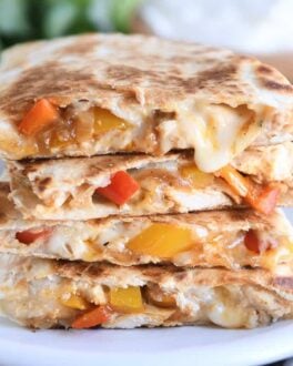 four chicken quesadilla triangles stacked on white plate