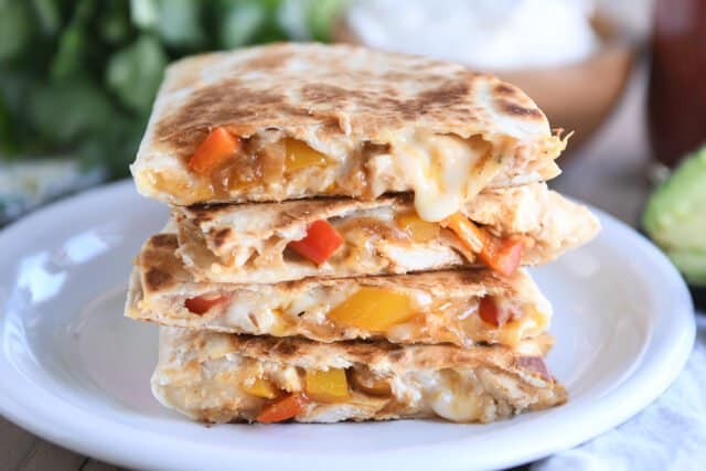 four chicken quesadilla triangles stacked on white plate