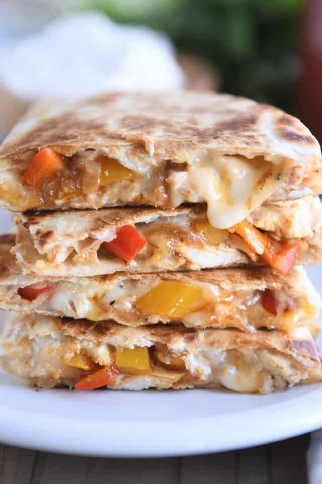 Four chicken quesadillas stacked on white plate.