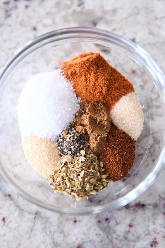 Small glass bowl with salt, cumin, garlic powder, onion powder, chili powder, oregano, and pepper.